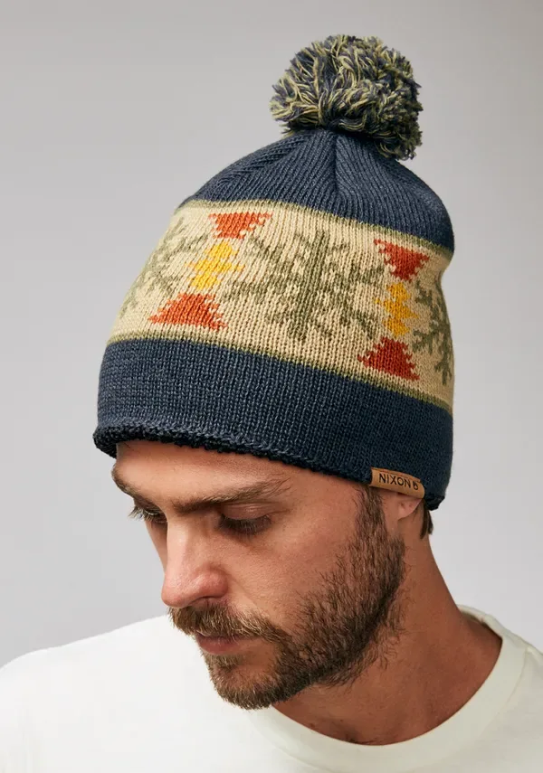 Model wearing a navy patterned pom-pom beanie, front three-quarter view