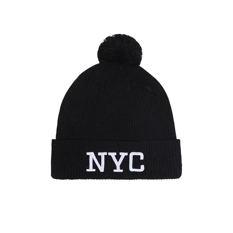 Black pom pom beanie with white nyc lettering on the cuff