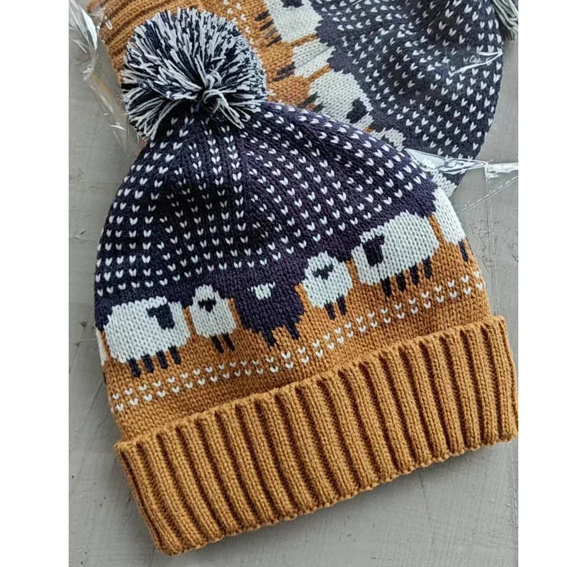 Close view of a blue and ochre sheep pattern beanie with pom pom