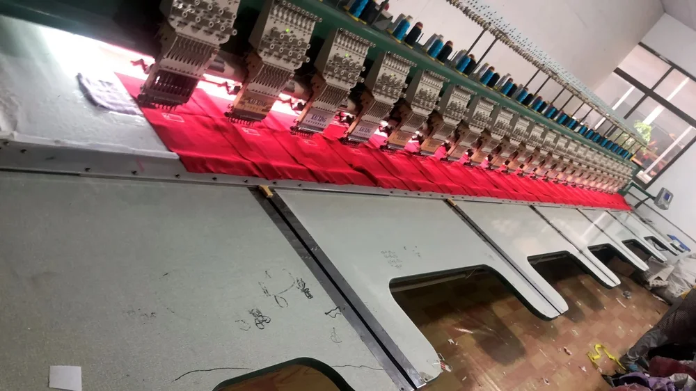 Multi head embroidery machine with red fabric held below the needle heads