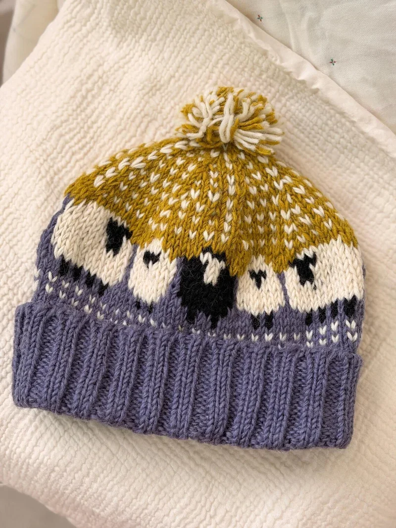 Mustard and lilac pom pom beanie with a knitted sheep motif