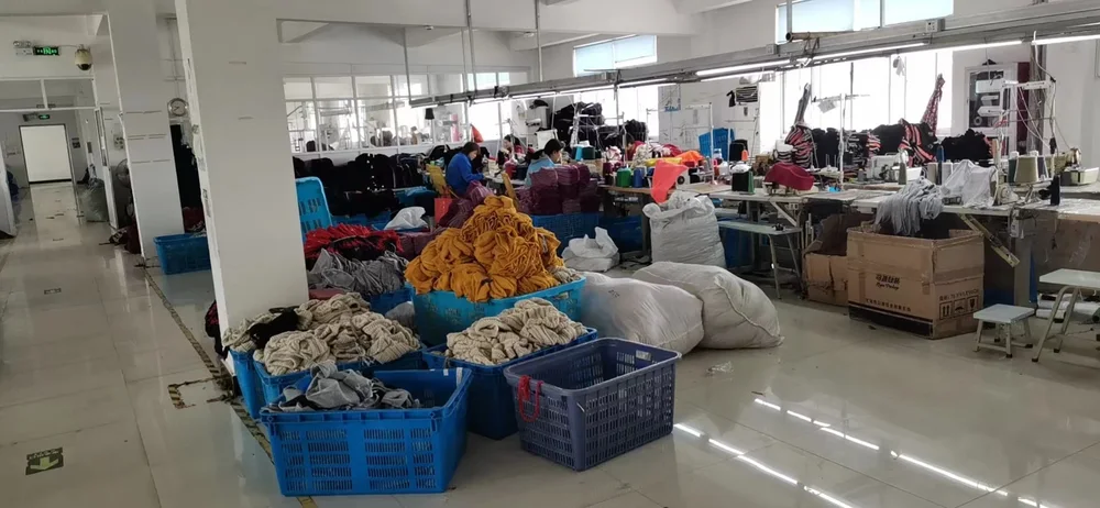 Textile workshop with workers and bins of colourful knit pieces